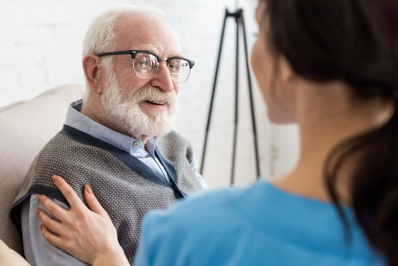 Care worker reassuring an elderly man at home