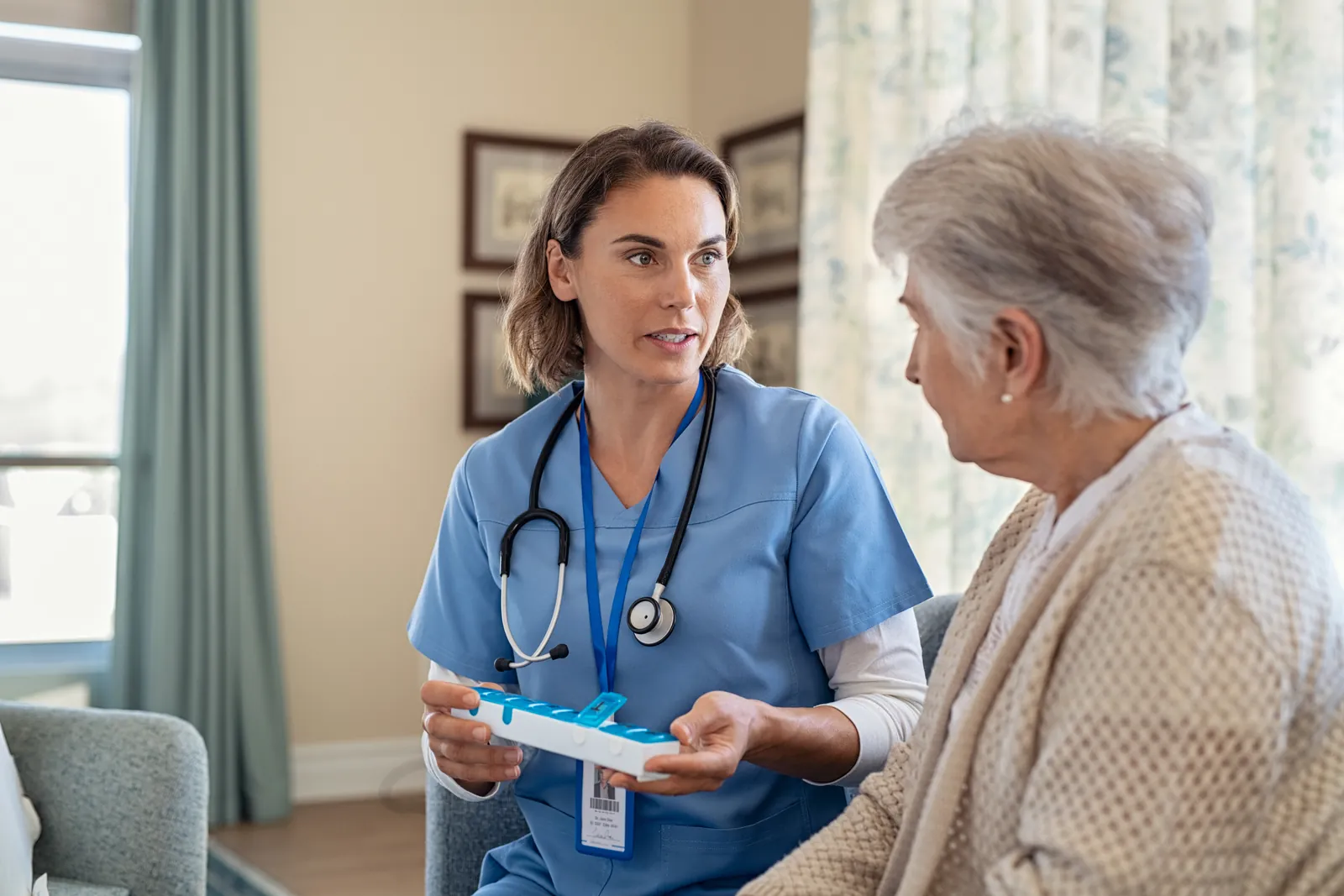 Nurse explaining a pill organiser to an elderly woman