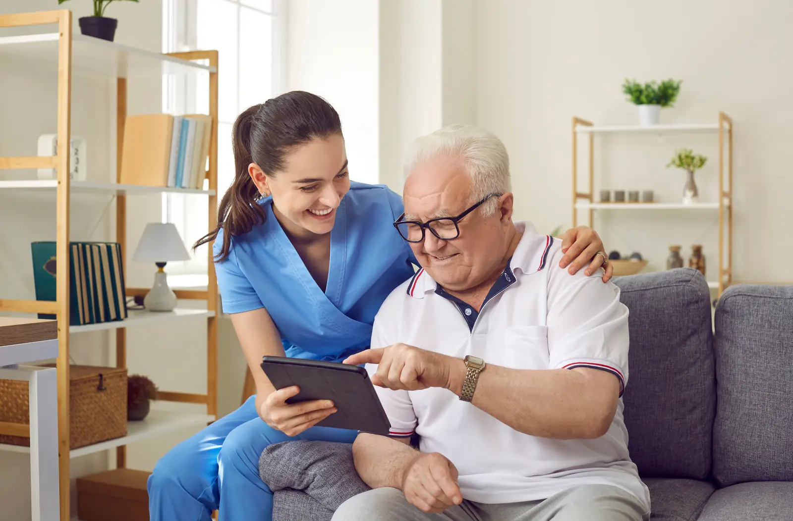 Care worker showing an older man something on a tablet at home